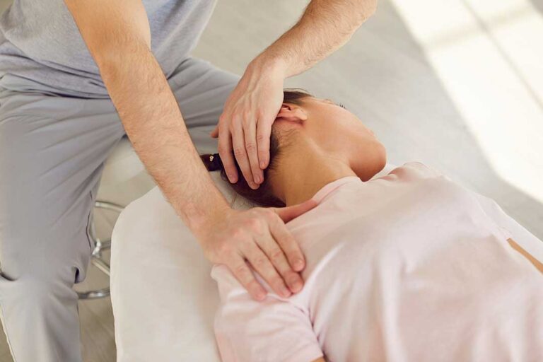 Pregnant woman lying comfortably on her side with cushions while receiving gentle back care.