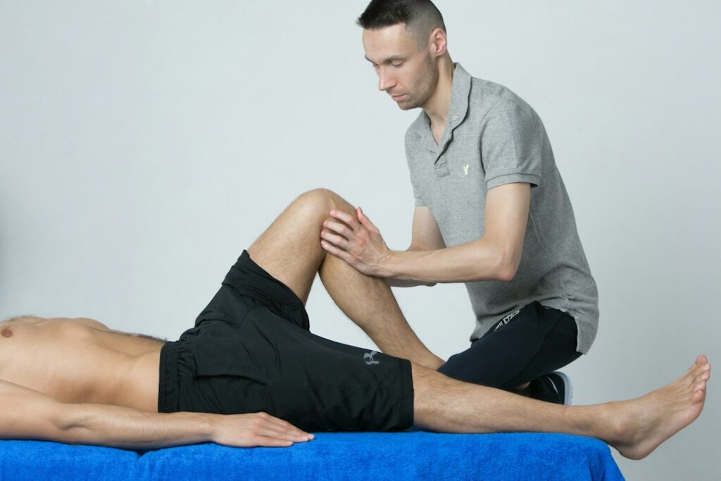 Athlete performs a guided balance exercise beside a treatment table during sports injury rehabilitation.