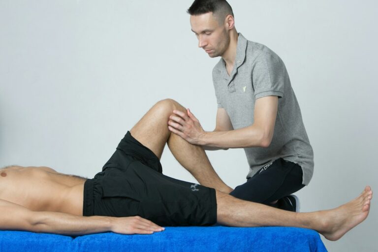 Athlete performs a guided balance exercise beside a treatment table during sports injury rehabilitation.